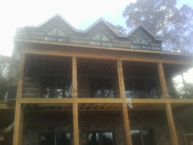 Dormers and porch framing on a large log home under construction — Roof Coating work by our crew in Weston
